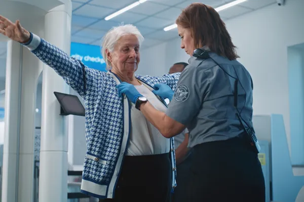 TSA agent checking woman at security checkpoint