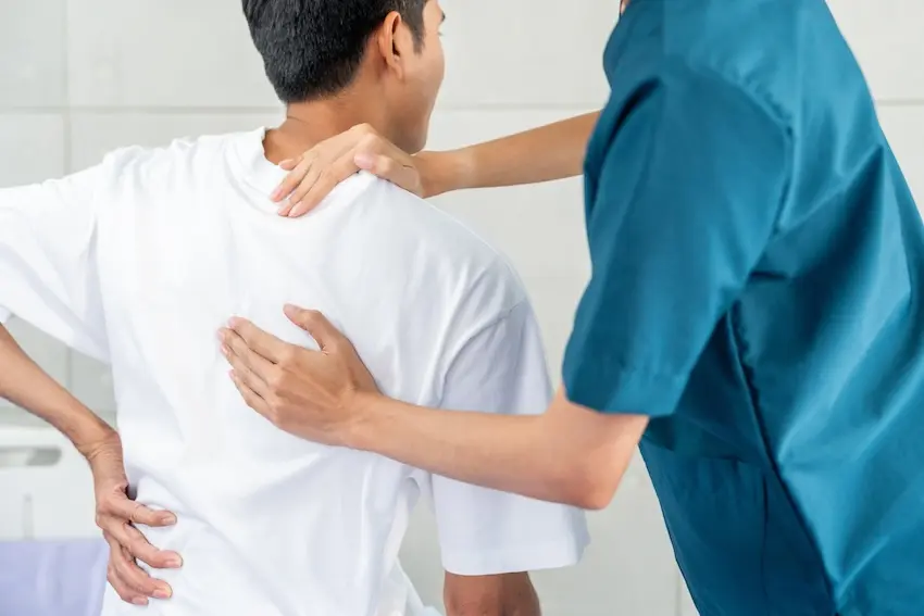 Licensed physical therapist guiding patient through therapeutic exercises for chronic back pain and spine rehabilitation
